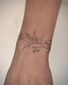 a person's hand with a flower tattoo on the left side of their wrist