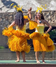 two women dressed in yellow hula skirts standing next to each other with their hands up