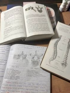 an open book sitting on top of a wooden table next to other books and papers