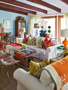 a living room filled with lots of furniture and colorful pillows on top of it's couches