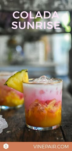 two glasses filled with drinks sitting on top of a wooden table next to pineapple slices