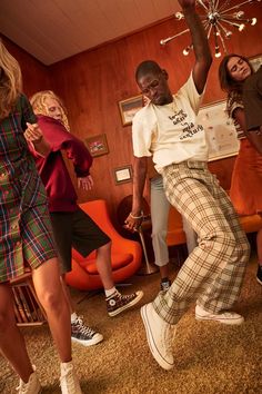 group of people dancing in a living room with lights on the ceiling and carpeted floor