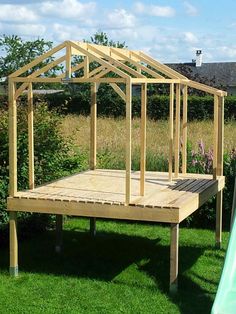 a wooden structure sitting on top of a lush green field