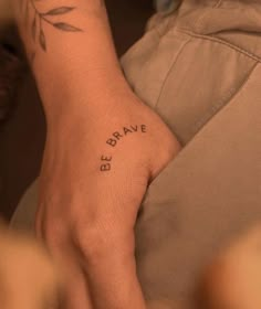 a person with a small tattoo on their wrist that says be brave in black ink