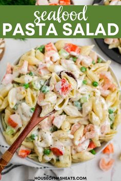 seafood pasta salad in a white bowl with a wooden spoon on the side and text overlay that reads seafood pasta salad