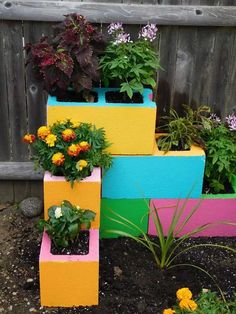 colorful planters are stacked on top of each other in front of a wooden fence