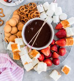 an assortment of snacks on a plate with strawberries, pretzels and marshmallows