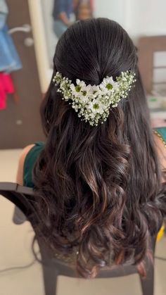 the back of a woman's head with flowers in her hair, sitting on a chair