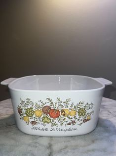 a white casserole dish with fruit painted on it