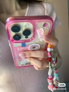 a woman is holding a pink case with flowers on it and beads around her wrist