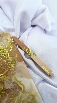 a close up of a gold tie on a white cloth with a knife sticking out of it