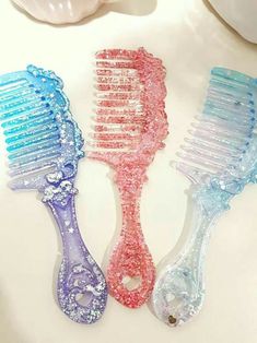 three different colored combs sitting next to each other on a white counter top,