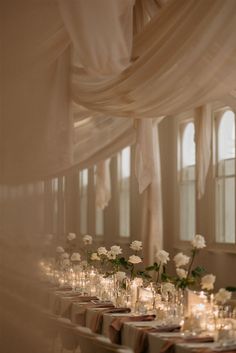 a long table with candles and flowers in vases next to each other on the tables