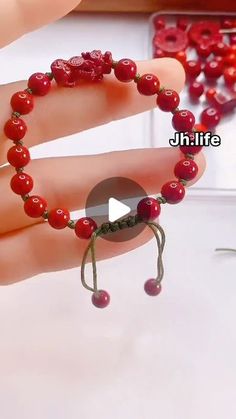 a hand holding a red beaded bracelet on it's fingers with beads attached to it