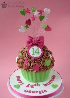 a birthday cupcake decorated with chocolate icing and pink ribbon, on top of a white plate