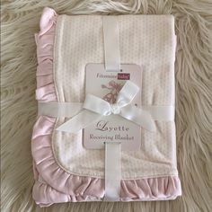 a pink blanket with white ruffles and a tag on the bottom that says layette receiving blankets