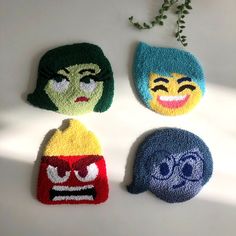 four knitted hats with faces on them