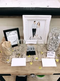 a wooden table topped with jars filled with candy and candies next to a framed picture