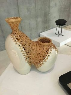 a white vase sitting on top of a table next to a black chair and phone