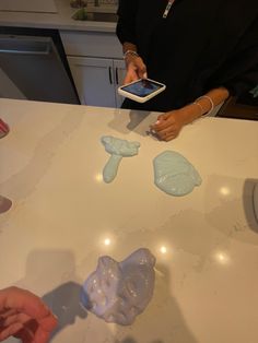 two people are making soap sculptures on a counter top with their cell phones in front of them