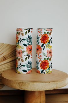 two vases sitting on top of a wooden table next to eachother with flowers painted on them