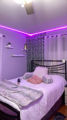 a bed room with a neatly made bed and purple lights on the wall above it