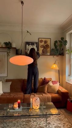 a woman sitting on top of a couch in a living room next to a window