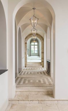 an arched hallway leading to the front door and entry way with light fixtures on either side