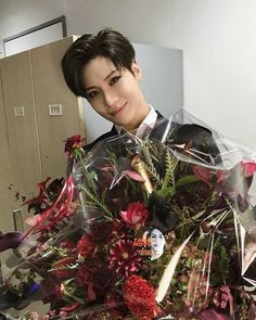 a woman holding a bouquet of flowers in an office cubicle with her face covered by plastic