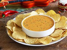 a white plate topped with tortilla chips next to a bowl of salsa sauce