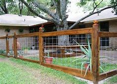 a wooden fence in front of a house with a large tree on the other side