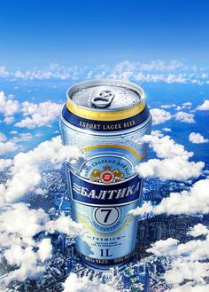 a can of beer floating in the air above clouds and cityscape with blue sky