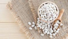 white beans in a wooden bowl and spoon on burlock