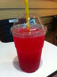 a red drink with a yellow straw in a plastic cup on a white counter top