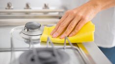 a person cleaning a stove top with a yellow cloth and a microniturmer