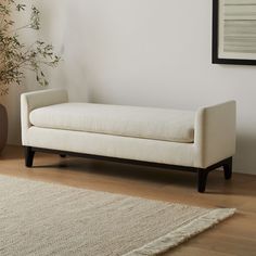 a white couch sitting on top of a wooden floor next to a potted plant