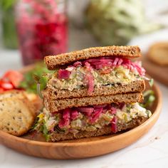 there is a sandwich on a plate with crackers and salad in the bowl next to it