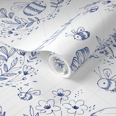 a blue and white wallpaper with flowers, bees and leaves on it's surface