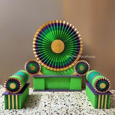 a green and yellow decoration with gold accents on it's sides, sitting on a table