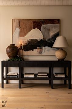 a table with two vases and a painting on the wall behind it in a living room