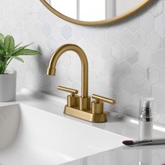 a bathroom sink with a gold faucet next to a mirror and toothbrush