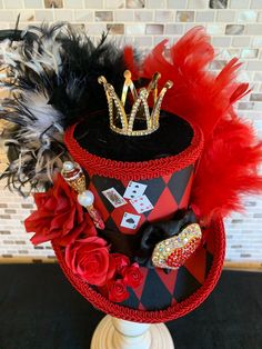 a red and black top hat with feathers on the bottom, surrounded by other items