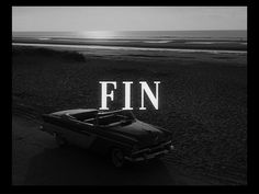 a black and white photo with the words fin in front of an old car at the beach