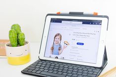 an ipad sitting on top of a desk next to a potted cacti