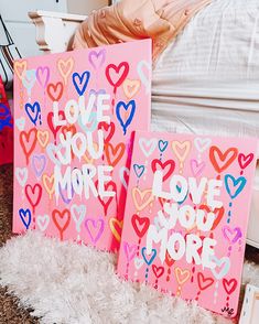 two pink canvass with hearts on them sitting on the floor next to a bed