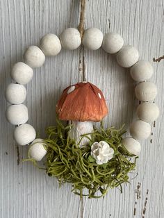 a wreath made out of white balls and moss with an orange mushroom sitting on top