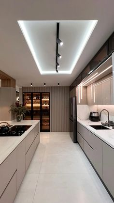 a modern kitchen with white counter tops and lights on the ceiling over the stove top