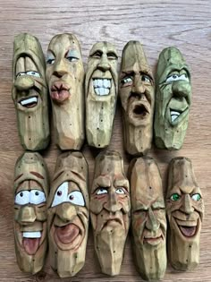 wooden carved faces are lined up on a table with eyes and mouths painted on them