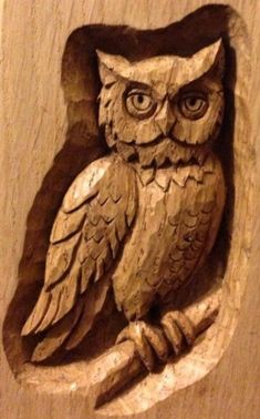 an owl is carved into the side of a wooden wall hanging on a wood panel