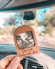 someone is holding up a wooden photo ornament in the back of a car